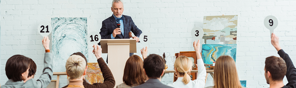 Auctioneer talking with microphone and looking at buyers with auction paddles during auction