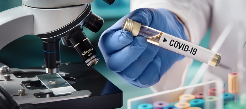 Photo d'un laborantin tenant un tube sur lequel est inscrit "Covid-19"